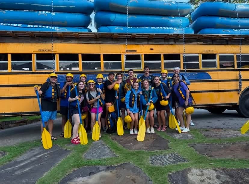 Youth rafting trip — life jackets, helmets, and paddles by the bus